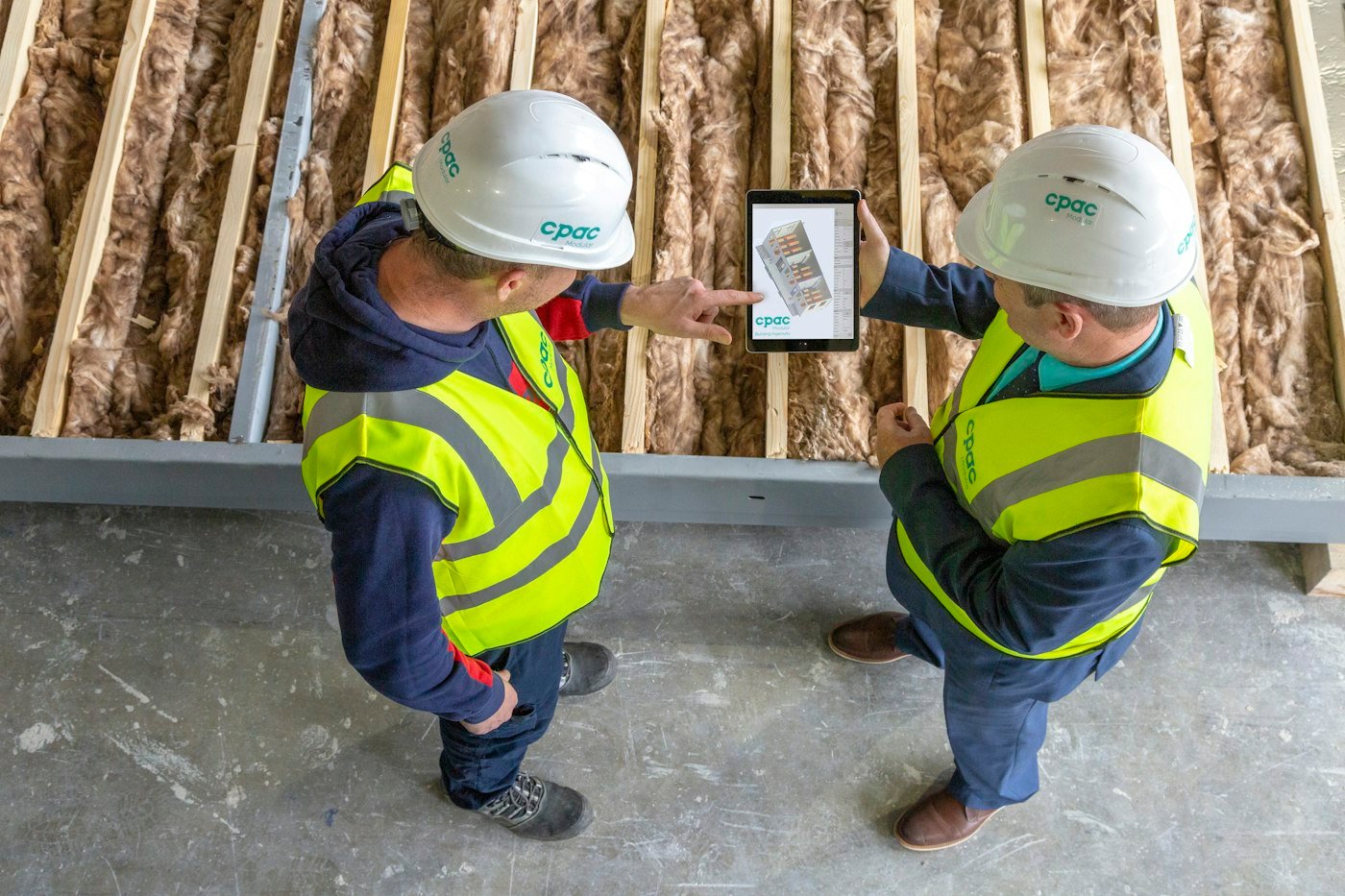 Deux artisans consultent un plan sur une tablette sur un chantier
